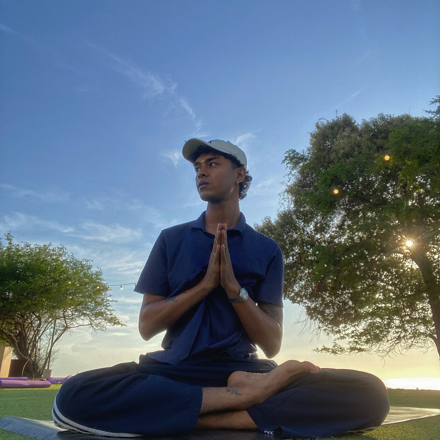 Saranagatha Das sentado en padmasana con las manos en anjali mudra, al atardecer